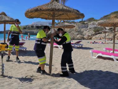 Els treballadors de la SAM instal·lant gandules i para-sols. 